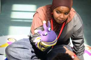 A tutor acts out a story using a puppet